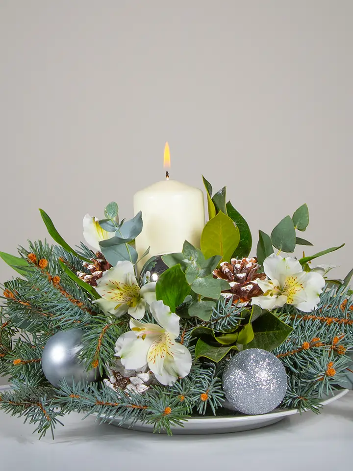 Centrotavola di fiori bianchi elementi natalizi e candela bianca close up